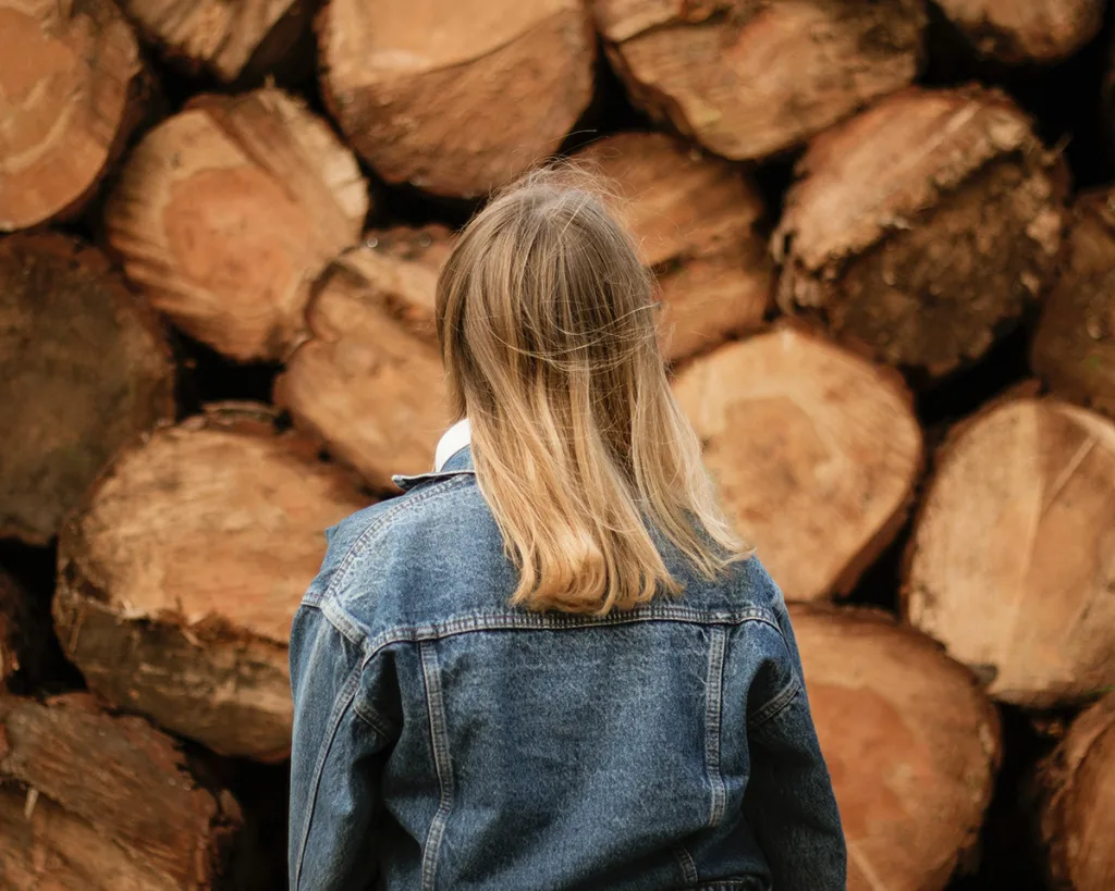 Blonde woman standing near lumbers during daytime