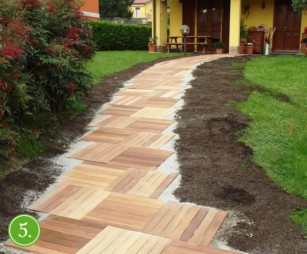 Terriccio steso ai lati delle piastrelle in legno per livellare il sentiero