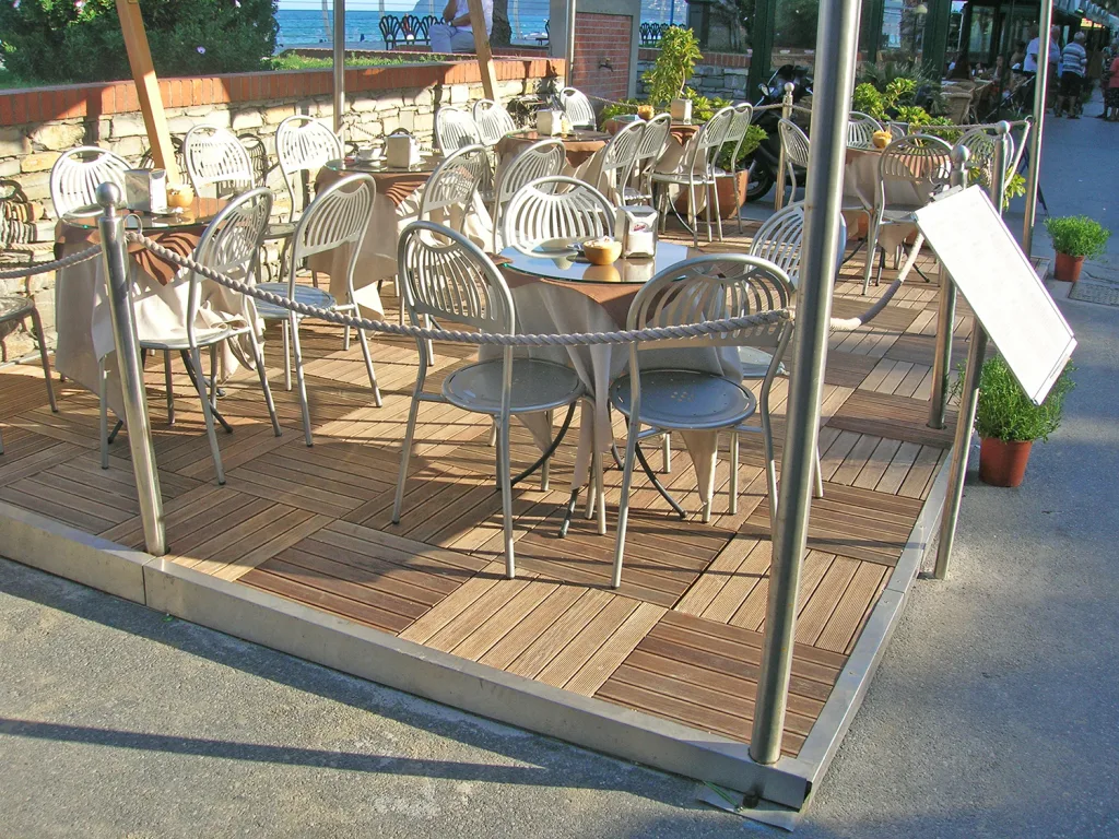 Dehors di un ristorante con pavimento in piastrelle di legno e arredi in legno