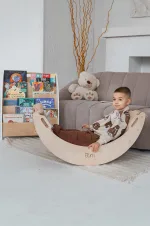 Bambino seduto nell'arco Pikler usato come dondolo in soggiorno
