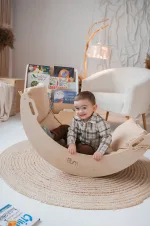 Bambino si dondola nell'arco Pikler in legno su un tappeto