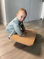 Bambino piccolo gioca a gattoni sulla balance board in legno