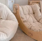 Dondolo CLASSIC con cuscino imbottito accanto a un pouf