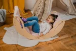 Bambina sdraiata nel dondolo Montessori SMILE sul pavimento in legno