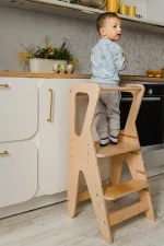 Bambino in piedi nella learning tower al piano di lavoro della cucina