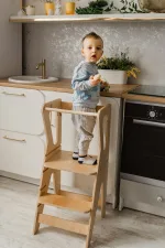 Bambino nella torre Montessori in legno aiuta in cucina