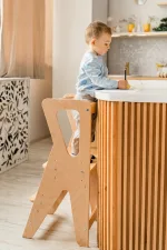 Bambino gioca all'isola della cucina in piedi sulla torre Montessori
