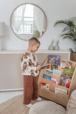 Bambino sceglie un libro dalla libreria Montessori in cameretta
