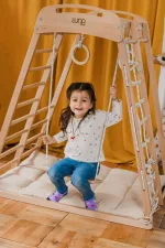 Bambina sull'altalena della palestra Montessori in legno di faggio