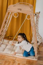 Bambina gattona sul materassino all'interno della palestra Montessori in faggio