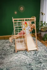 Bambina si arrampica sulla rete della palestra Montessori in legno