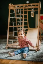 Bambina seduta in fondo allo scivolo della palestra Montessori da interno