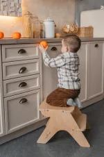 Bambino sale sullo sgabello in legno per arrivare al piano della cucina